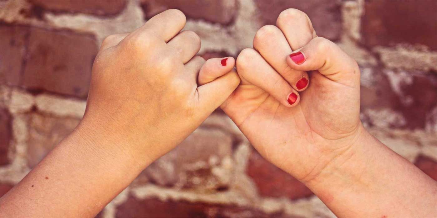 Photo of two hands grabbing fingers to make a pinky promise