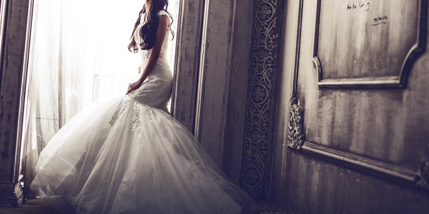 Photo of a bride at a window getting ready for her wedding