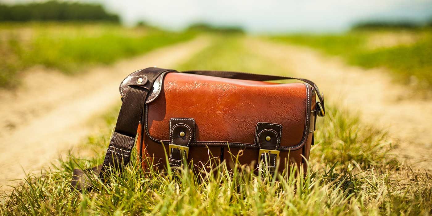 Photo of a leather bag on a grass and dirt lane