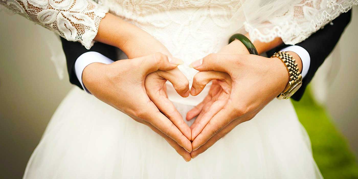 Photo of a bride and groom with their hands shaped as hearts