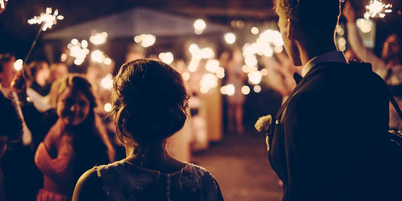Photo of a bride and groom walking onto the dance floor with guests waving sparklers